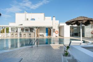 a large white building with a swimming pool at Bella Santorini Hotel in Perivolos