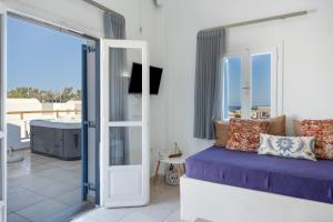 a bedroom with a bed and a balcony with a tub at Bella Santorini Hotel in Perivolos