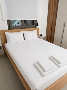 a white bed with two white towels on it at Elina's Era Lounge Apartment in Palekastron