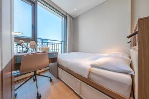 a bedroom with a bed and a desk and a window at Weave Suites - Sunyu Parkside in Seoul
