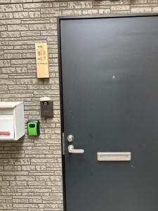 a black door on a brick wall with a sign on it at 馨誠小屋201 in Tokyo