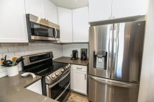 a kitchen with white cabinets and a stainless steel refrigerator at B205 - Ocean Escape in Oceanside
