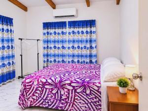 a bedroom with a purple and white bed and a window at Mouare Hideaway in Arutanga