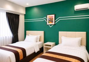 two beds in a room with a green wall at Alami Garden Hotel in Shah Alam +63 photos
