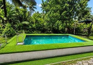 a swimming pool in a yard with green grass at Sheen Villa Homestay in Varkala