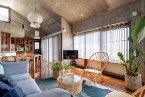 a living room with a couch and chairs and a tv at Alumina アルミナ in Kin