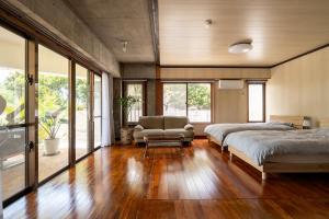 a bedroom with two beds and a chair and windows at Alumina アルミナ in Kin