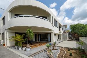 a large white building with plants in front of it at Alumina アルミナ in Kin