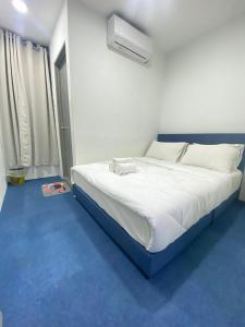 a bedroom with a white bed with a blue floor at Enviropath Hotel now Bayan Nur Inn in Kampong Pengkalan
