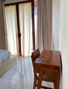 a room with a wooden table and a bed and window at Sariuma babadan in Badung