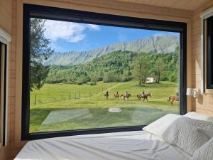 a bedroom with a large window with people riding horses at BONIS - Nidi nel Bosco in Montemaggiore