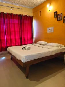 a bed in a room with a red curtain at VISHAKA RESIDENCY yercaud in Siddhma