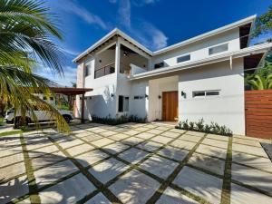 a white house with a palm tree in front of it at Casa Rivera - 4 Bedrooms in West Bay