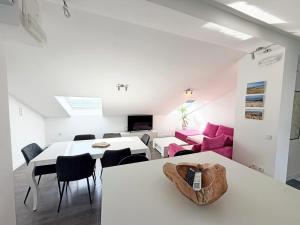 a living room with a white table and pink furniture at Family Apartments Monika - sea view - heated pool in Punat