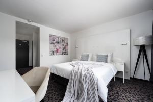 a white bedroom with a large bed and a chair at MICE Collection Hotel Trier Business- und Stadthotel an der Mosel nahe SWT Arena und Viking Anleger in Trier
