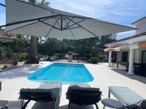 a swimming pool with an umbrella and chairs and a table andools at VILLA MESSILIA Guest Rooms French Riviera in Saint-Raphaël