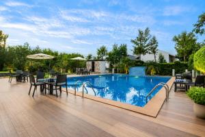a swimming pool with tables and chairs on a wooden deck at The Blossom Resort - Chikmagalur in Chikmagalūr