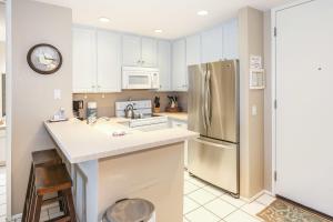 a kitchen with white cabinets and a stainless steel refrigerator at E201 - Tropical Shores in Oceanside