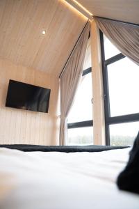 a bedroom with a bed and a tv on a wall at Craftowe domki in Rusinowo