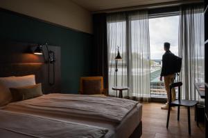 a man standing in a hotel room looking out the window at Autohalle Hotel in Andelfingen