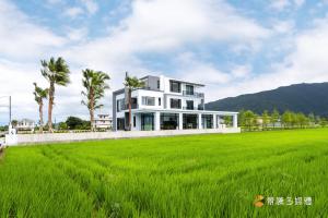 a large white house in a field of grass at 亮Villa in Sanxing