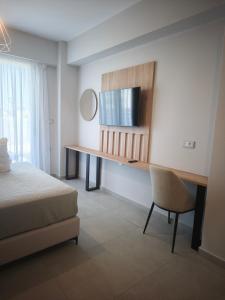 a bedroom with a bed and a desk with a television at Salt & Light House in Tigaki