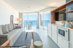 a living room with a couch and a kitchen with the ocean at The Salmar - Adults Only in San Miguel de Abona