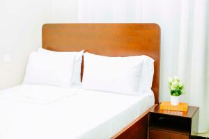 a bed with two white pillows and a wooden headboard at Sastar Homes in Iringa