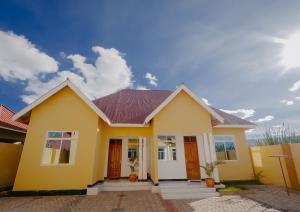 a yellow house with a red roof at Sastar Homes in Iringa