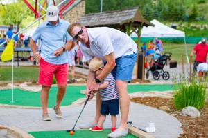a man teaching a little boy how to play golf at 323 Beaver Creek Lodge in Avon