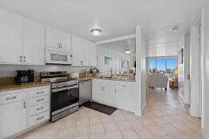 a kitchen with white cabinets and a stove top oven at D20 - Beachfront Delight in Oceanside