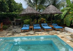 a swimming pool with chairs and a table and an umbrella at Villa Rita in Gede