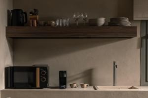 a kitchen counter with a microwave and a shelf with dishes at Domus Gaia Suites in Nikiti