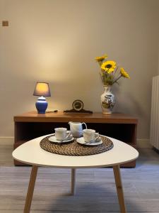 a coffee table with two cups and a vase with flowers at Spacious e Modern Comfort Near Center in Lucca +6 photos