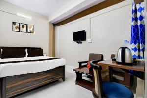 a bedroom with a bed and a desk and a television at Super Collection O NIT More Adityapur Formerly Hotel Subheksha in Jamshedpur