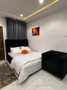 a bedroom with a bed and a black chair at Blu in Ikeja