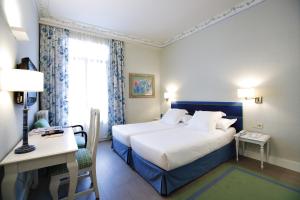 a hotel room with a bed and a desk and a window at Hotel Niza in Donostia-San Sebastián