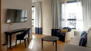 a living room with a desk and a chair and a couch at Sercotel Sevilla Don Luciano in Seville