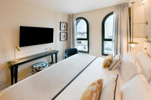 a bedroom with a large white bed and a tv at Sercotel Sevilla Don Luciano in Seville