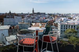 a table and chairs on a balcony with a view of a city at Sercotel Sevilla Don Luciano in Seville