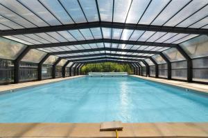 an indoor swimming pool with a glass ceiling at 11.Les tilleuls option Clim -6 pers in Calviac +29 photos
