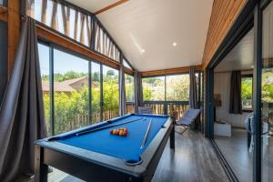 a pool table in a room with windows at Chalet L'entékia - Billard et Spa in Corcieux