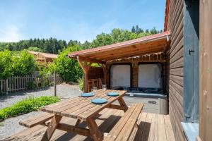 a wooden picnic table on a deck next to a house at Chalet L'entékia - Billard et Spa in Corcieux