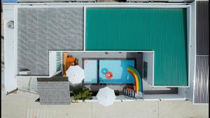 a large green building with a pool with a rainbow at V house 1 in Ban Huai Yai