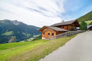 a wooden house on a hill next to a road at Innerdurachhof in Santa Valpurga