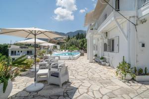 a patio with chairs and an umbrella and a pool at Xenia & Antonis in Nikiana