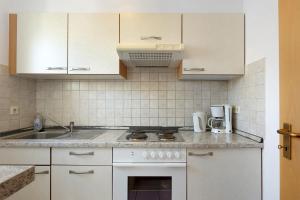 a kitchen with white cabinets and a stove top oven at Apartment 44 in Bad Dürrheim