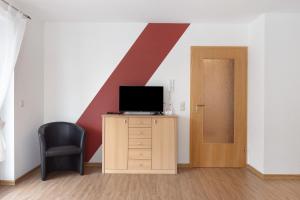 a room with a tv and a chair and a door at Apartment 45 in Bad Dürrheim