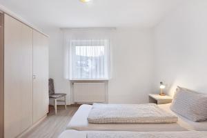 a white bedroom with a bed and a window at Apartment 30 in Bad Dürrheim