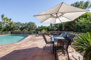 a patio with a table and an umbrella next to a pool at Apartamento II Els Cucons in Sant Pere de Ribes
